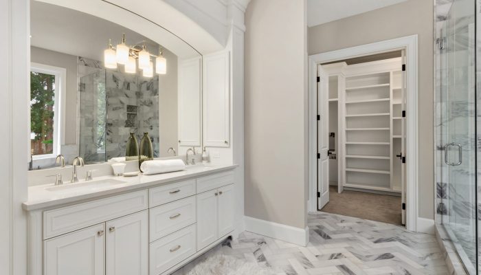 An Ensuite bathroom of a master bedroom, with wide vanity area, a shower area with glass door, and a marble herringbone floor