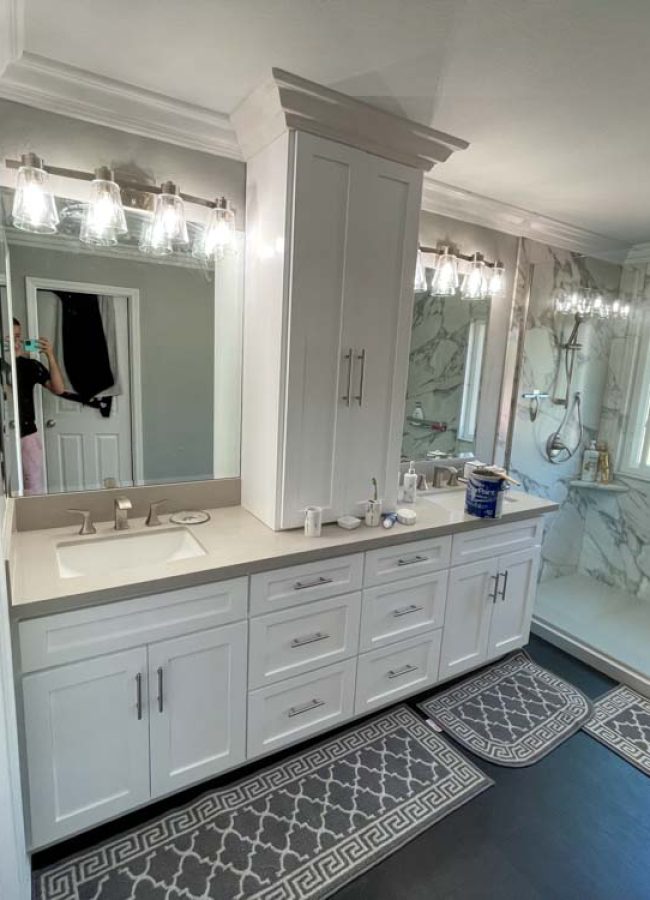 Remodeled bathroom, tiled shower backsplash, vanity lights, and a vanity cabinet and drawer, with two sink
