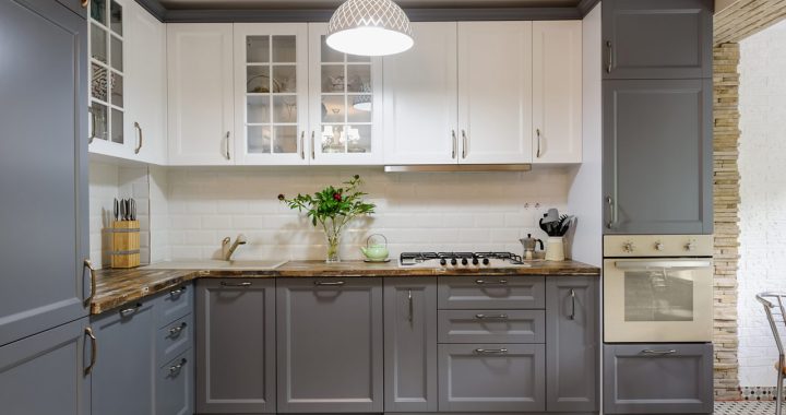 Monochrome kitchen: gray and white cabinets, granite countertop, and an elegant hanging light fixture